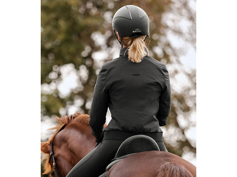 Frau auf Pferd von hinten mit schwarzem Reitblouson