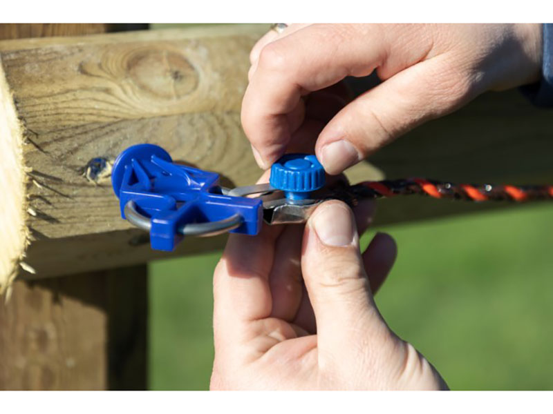 Hände am Weidezaun mit blauem Seil-/Litzen-Schnellverbinder