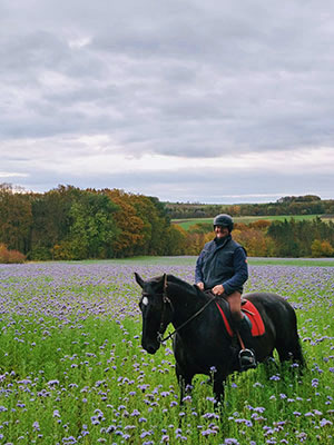Stefan Veh beim Wanderritt mit Molly auf einer violett blühenden Wiese